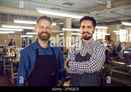 Portrait von glücklichen Schuhfabrikarbeitern, die in der Werkstatt stehen und Blick auf die Kamera Stockfoto