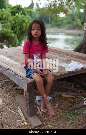 Don Det, Laos - 5. April 2013: Porträt eines jungen Mädchens, das auf einer Bank sitzt. Stockfoto