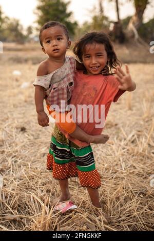 Don Det, Laos - 4. April 2013: Porträt eines unbekannten jungen Mädchens, das ein Kleinkind trägt. Stockfoto