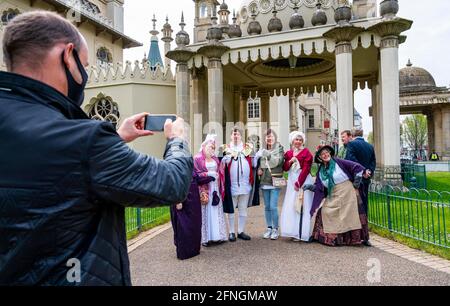 Brighton UK 17. Mai 2021 - Besucher posieren mit Mitarbeitern in Regency-Kostümen im Royal Pavilion in Brighton, der heute morgen wieder für die Öffentlichkeit geöffnet wurde, als die nächste Stufe der Sperrungsbeschränkungen heute in ganz England gelockert wurde : Credit Simon Dack / Alamy Live News Stockfoto