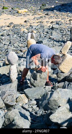 Kieselsteinskulpturen am Strand von St. Ives, Cornwall. Kiesel Bildhauer bei der Arbeit. Rock Balancing. Konzentration. Stockfoto