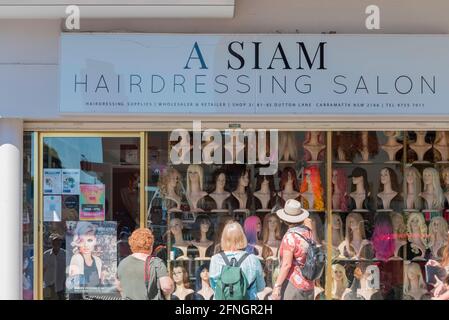 Drei weiße australische Frauen blicken auf das Fenster eines Friseursalons und Perückenladens im australischen Vorort Cabramatta in Sydney Stockfoto