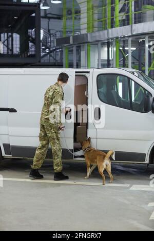 Rückansicht eines Militärs mit Hund, der die Ladung kontrolliert Im LKW vor der Auslieferung Stockfoto