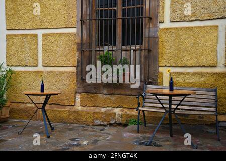 Patio des lokalen El Café Azul mit Bistrotischen und einer Holzbank an einer ockerfarbenen Steinmauer in der Geisterstadt Real de Catorce in Mexiko. Stockfoto