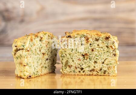 Zwei Hälften eines frisch gebackenen Muffins mit Speck und Dill auf einem Schneidebrett. Nahaufnahme. Stockfoto