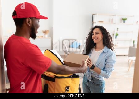 Schwarzer Lieferer nimmt die Box aus dem Thermorucksack Stockfoto