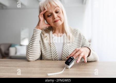 Ältere Frau, die Oximeter zu Hause verwendet. Gesundheitskonzept Stockfoto