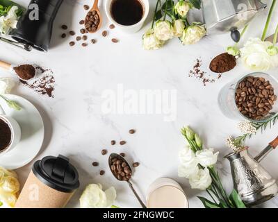 Flacher Rahmen aus Kaffee, Blumen, verschiedenen Utensilien für die Herstellung von Kaffee und Tassen Kaffee auf weißem Marmor Hintergrund. Kaffeekonzept. Draufsicht. Kopie sp Stockfoto
