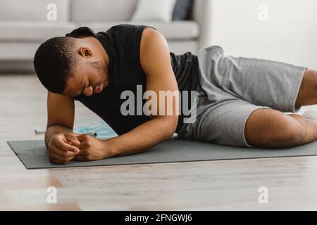 Black Fitness Mann Gefühl Schlecht Während Des Trainings Zu Hause Stockfoto