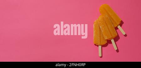 Mango- oder Karamell-Eis-Sticks auf rosa Hintergrund Stockfoto