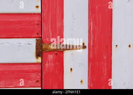 Abschnitt aus rot und weiß bemalten Holzhütte mit rostigen Scharnier Stockfoto