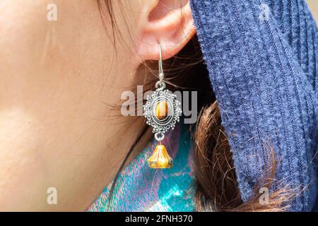 Nahaufnahme eines Frauenohrs mit schönen Ohrringen mit Mineralstoffen Edelstein Stockfoto