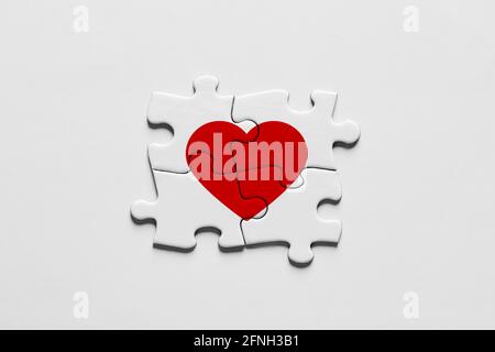 Vier Puzzleteile verbinden sich miteinander und bilden eine Herzform. Stockfoto