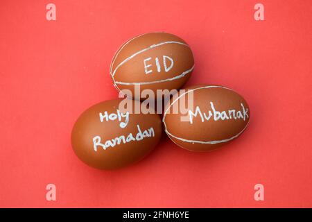 Der heilige Ramadan und Eid Mubarak geben Typografie auf dem Ei ab. Roter isolierter Hintergrund. Stockfoto