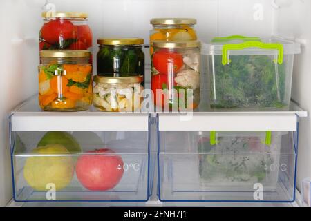 Verschiedene Gläser hausgemachtes eingelegtes Gemüse und andere Produkte stehen im Kühlschrank. Fermentierte gesunde natürliche vegetarische Nahrung Konzept. Stockfoto