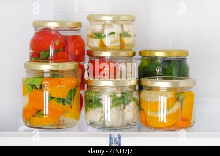 Verschiedene Gläser hausgemachtes eingelegtes Gemüse stehen im Kühlschrank. Fermentierte gesunde natürliche vegetarische Nahrung Konzept. Stockfoto