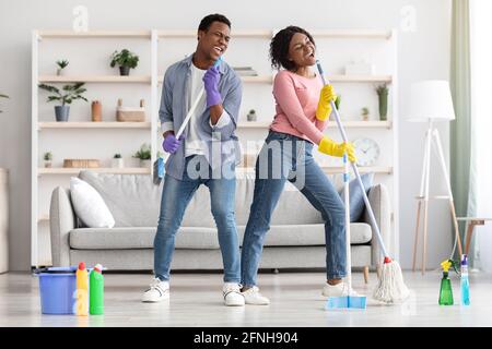 Lustige afroamerikanische Familie, die Spaß beim Reinigen der Wohnung hat Stockfoto