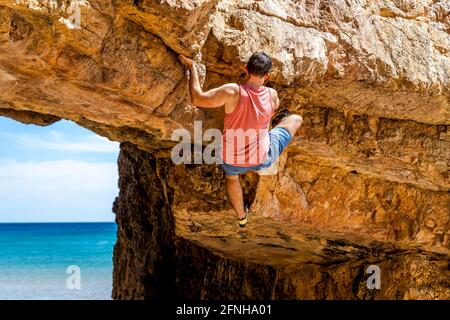 Junge Kletterer klettern sicher auf eine gelbe Klippe an der Algarve, Portugal Stockfoto