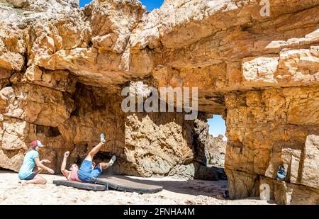 Ein Kletterer, der auf Sicherheitsmatten am Strand, an der Algarve, in Portugal und in Europa vom Felsen fällt Stockfoto