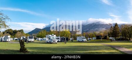 Keswick Caravan- und Camping Club-Platz mit einer schneebedeckten Skiddaw im Hintergrund. Ein früher Frühlingsmorgen, als der Campingplatz zum Leben erweckt wird. Stockfoto