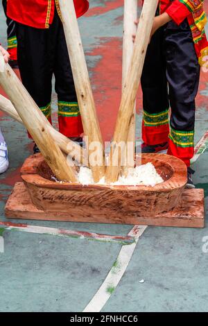 Eine Gruppe von Menschen, die mit Holzstäben klebrigem Reis hammerten Für die Herstellung von Reiskuchen mit Merkmalen der Guangxi Zhuang Nationalität Stockfoto