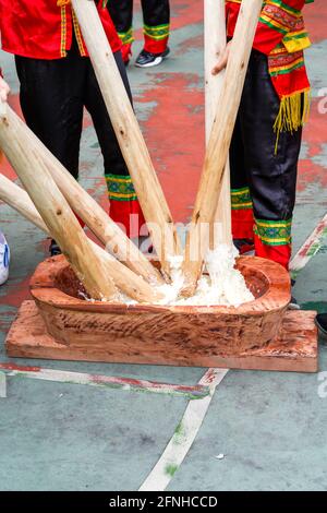 Eine Gruppe von Menschen, die mit Holzstäben klebrigem Reis hammerten Für die Herstellung von Reiskuchen mit Merkmalen der Guangxi Zhuang Nationalität Stockfoto