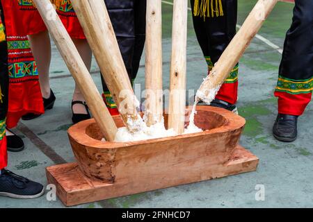 Eine Gruppe von Menschen, die mit Holzstäben klebrigem Reis hammerten Für die Herstellung von Reiskuchen mit Merkmalen der Guangxi Zhuang Nationalität Stockfoto