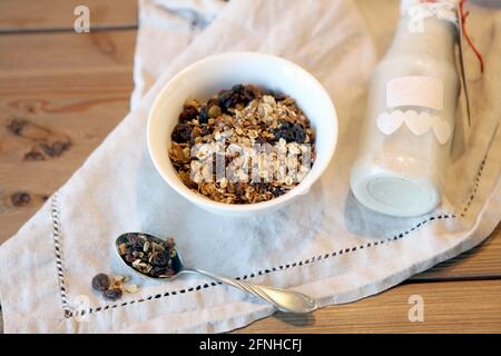 Flasche frische Milch mit Hafer und Vollkornflocken auf Holztisch. Schüssel Müsli hausgemachte Müsli in einer Schüssel und Milch oder Joghurt auf rustikalen w Stockfoto