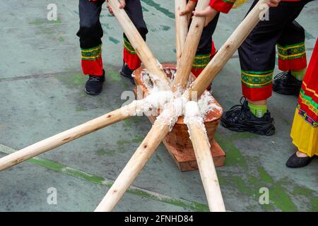 Eine Gruppe von Menschen, die mit Holzstäben klebrigem Reis hammerten Für die Herstellung von Reiskuchen mit Merkmalen der Guangxi Zhuang Nationalität Stockfoto