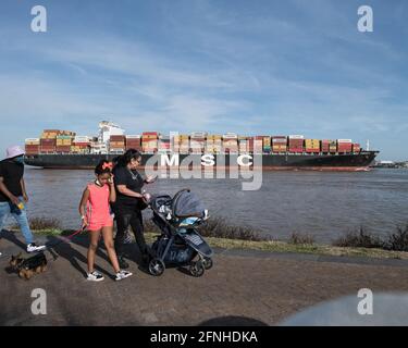 Die Menschen beobachten, wie ein riesiges MSC-Containerschiff mit globaler Ladung auf dem Mississippi River in der Nähe von New Orleans, Louisiana, vorbeifährt. Stockfoto