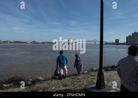 Die Menschen beobachten, wie ein riesiges MSC-Containerschiff mit globaler Ladung auf dem Mississippi River in der Nähe von New Orleans, Louisiana, vorbeifährt. Stockfoto