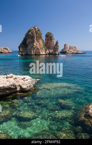 Scopello, Trapani, Sizilien, Italien. Blick über die felsige Bucht auf die Faraglioni, eine Reihe von Schornsteinen im Golf von Castellammare vor dem Tonnara di Scopello. Stockfoto