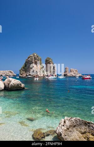 Scopello, Trapani, Sizilien, Italien. Blick über die felsige Bucht auf die Faraglioni, eine Reihe von Schornsteinen im Golf von Castellammare vor dem Tonnara di Scopello. Stockfoto