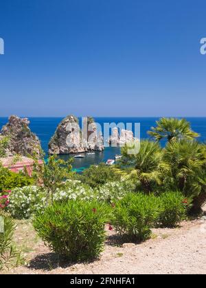 Scopello, Trapani, Sizilien, Italien. Blick über die felsige Bucht auf die Faraglioni, eine Reihe von Schornsteinen im Golf von Castellammare vor dem Tonnara di Scopello. Stockfoto