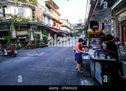 Ein männlicher Straßenverkäufer bereitet Speisen an einem Imbissstand im Freien in der Chinatown-Gegend von Bangkok, Thailand, zu Stockfoto