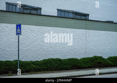 Ein blaues Straßenschild vor einer weißen Hauswand. Stockfoto