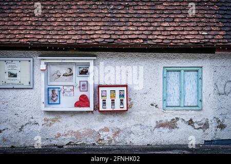 Altes baufälliges Haus am Straßenrand mit Kaugummimaschine aus Kindheitstagen in der Kleinstadt Andechs. Stockfoto