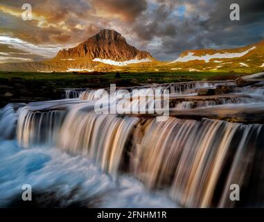 Wasserfall auf Reynolds Creek am Logan Pass mit Mt. Reynolds und Sonnenaufgang, Glacier National Park, Montana Stockfoto