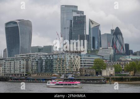 Skyline-Architektur der Stadt London vom Südufer der Themse mit grauem Himmel, Mai 2021, mit vorbeifahrenden Ausflugsbooten Stockfoto