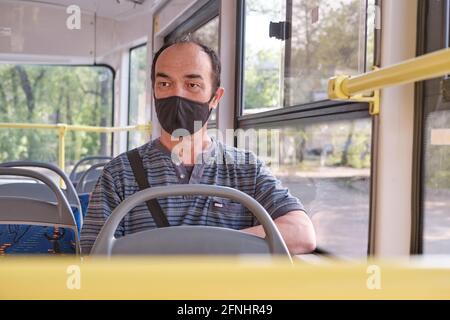 Nahaufnahme eines älteren asiatischen Mannes mit schwarzer Gesichtsmaske in öffentlichen Verkehrsmitteln. Stockfoto