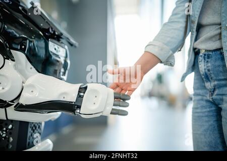 Junge Frau schüttelt eine moderne Roboterhand Stockfoto