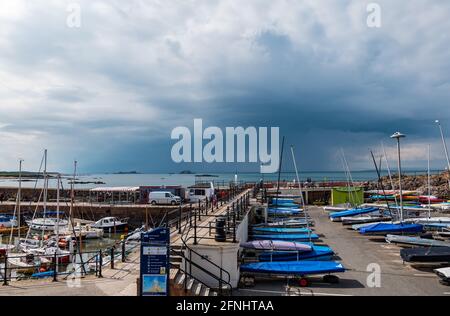 North Berwick, East Lothian, Schottland, Vereinigtes Königreich, 17. Mai 2021. Wetter in Großbritannien: Dunkle Wolken in stürmischem Himmel nähern sich über dem Firth of Forth, während Boote im Hafen der Küstenstadt noch in Sonnenschein gebadet werden Stockfoto