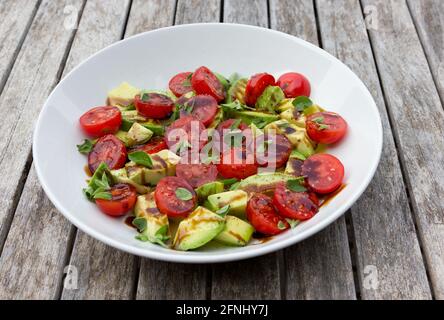 Tomaten- und Avocado-Salat mit Kräutern und Balsamico-Essig. Stockfoto