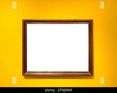 Natürlicher brauner Holzbilderrahmen mit ausgeschnitter Leinwand auf horizontaler Ebene Gelbe Wand Stockfoto