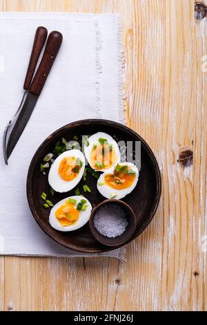 Halbierte hartgekochte Eier auf dem Teller auf einem rustikalen Holztisch, Draufsicht, Keto-Diät-Frühstück Stockfoto