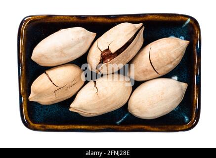 Draufsicht auf ungeschälte Pekannüsse im Schalenausschnitt Weißer Hintergrund Stockfoto