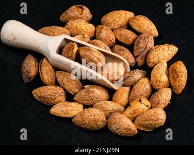 Holzlöffel in gebratenen Mandelblättchen auf schwarzem Teller Stockfoto