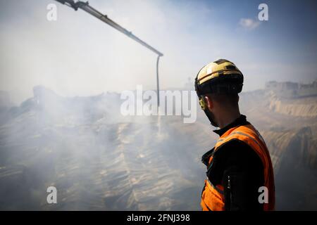 Gaza-Stadt, Palästina. Mai 2021. Ein palästinensischer Feuerwehrmann beteiligt sich an den Bemühungen, ein Feuer auf eine Schwammfabrik zu löschen, nachdem sie im nördlichen Gazastreifen von israelischen Artilleriebünden getroffen wurde, so Zeugen. (Foto von Nidal Alwaheidi/SOPA Images/Sipa USA) Quelle: SIPA USA/Alamy Live News Stockfoto