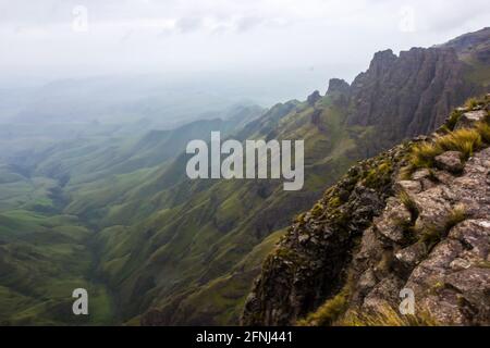 Blick von den hohen Gipfeln der Drakensberger Berge an der Grenze zwischen Südafrika und Lesotho, mit den grünen Hügeln und Bergen darunter Stockfoto