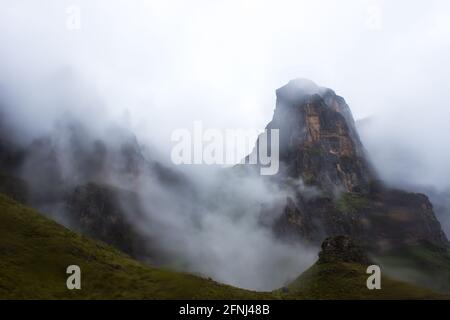 Die hohen Basaltgipfel der Drakensberg Mountains in Südafrika, teilweise verdeckt durch dichten Nebel, der sich um sie herum sammelt Stockfoto